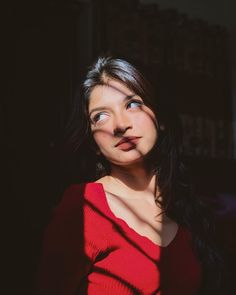 a woman in a red shirt is making a face with her shadow on the wall