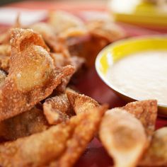 some fried food on a red plate with a bowl of dipping sauce in the background