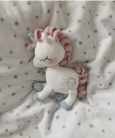 a crocheted unicorn laying on top of a bed