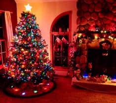 a living room decorated for christmas with a lit tree and fire place in the corner