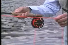 a man holding a fishing rod while standing next to a body of water with red lines on it