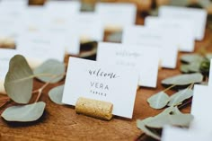 place cards are placed on top of wooden boards with eucalyptus leaves and greenery around them