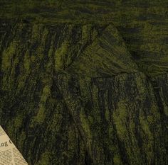 a newspaper laying on top of a bed next to a green and black bedspread