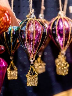 colorful ornaments are hanging from strings on the wall in front of some lights and sequins