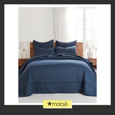 a bed with blue sheets and pillows in a room next to a window that reads macy's