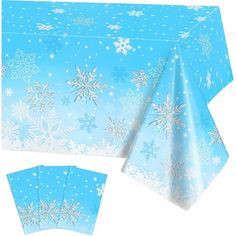 a blue table cloth with snowflakes on it and four napkins in front