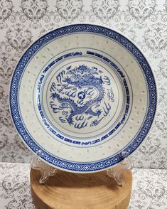 a blue and white plate sitting on top of a wooden stand in front of a wall