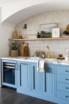 a kitchen with blue cabinets and white counter tops, along with pictures on the wall