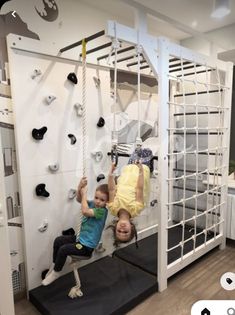 two children are climbing up and down the wall in a room that has white walls