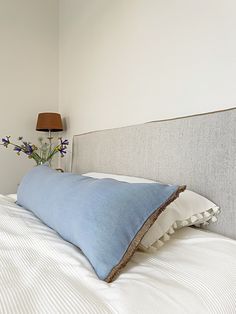 a blue pillow sitting on top of a white bed