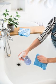 a woman is washing her hands in the bathroom sink with blue cloths on it