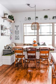 a dining room table with four chairs and a bench in front of the window that says yum