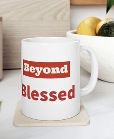 a white coffee mug sitting on top of a counter next to a bowl of fruit