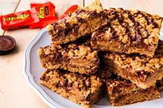 a white plate topped with granola bars next to chocolate chips and a candy bar