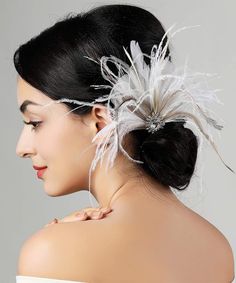 a woman wearing a white dress with feathers on her head and hair comb in the shape of a flower