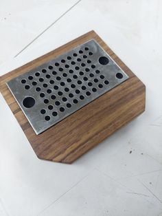 a metal grater sitting on top of a wooden cutting board with holes in it