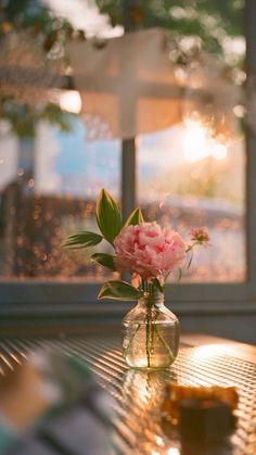 a vase filled with pink flowers sitting on top of a table next to a window