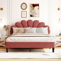 a bed with pink headboard and pillows in a white walled room next to two pictures on the wall