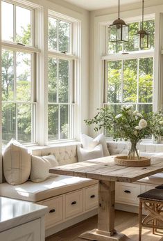 a living room filled with lots of windows next to a wooden table and white couches