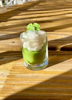 a glass filled with green liquid on top of a wooden table covered in white flowers