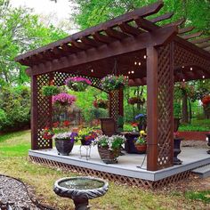 an outdoor gazebo with potted plants and flowers on the ground next to it