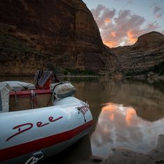 an inflatable raft sitting on the shore of a river with mountains in the background