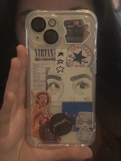 a person holding up a clear case with various stickers on the back of it