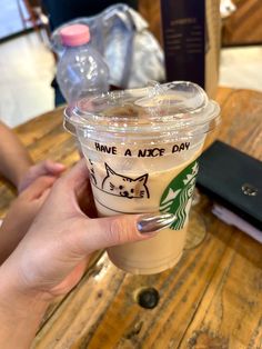 a person holding up a starbucks cup with cats on the side and have a nice day written on it