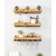 two wooden shelves with wine glasses on them and a potted plant in the corner