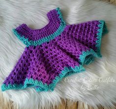 a purple and green crocheted dress laying on top of a white rug