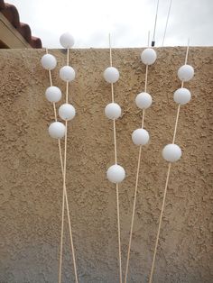 a group of white balls sitting on top of a wooden stick next to a wall