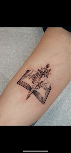 a tattoo on the arm of a woman with an open book and flowers in it