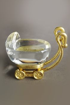 a gold plated glass baby carriage with wheels and handles, on a gray background