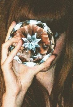 a woman holding up a crystal ball in front of her face