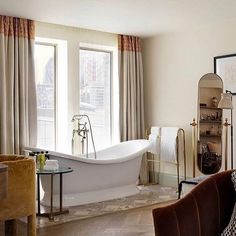 a bath tub sitting next to a window in a living room filled with furniture and decor