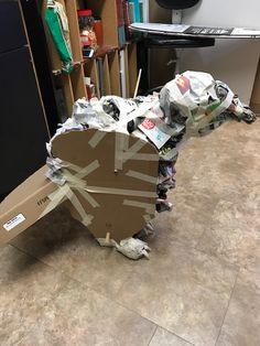 an animal made out of cardboard sitting on the floor