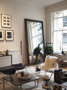 a living room filled with lots of furniture and large mirrors on the wall above them