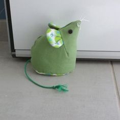 a green stuffed animal mouse sitting on the floor