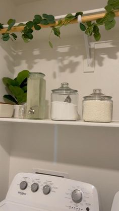 a white washer sitting next to a dryer on top of a wooden shelf