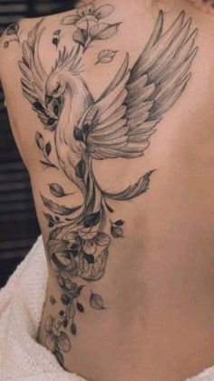 a woman's back with a bird tattoo on it