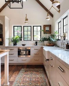 a kitchen with white cabinets and wooden floors, an area rug on the hardwood floor