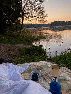 a person laying on a blanket next to a body of water