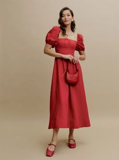 a woman in a red dress is holding a handbag