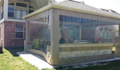 a house with a covered patio in front of it on the grass and next to a brick building