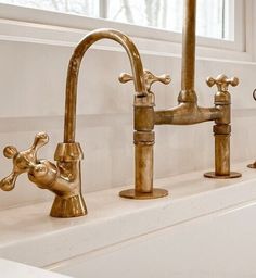 two faucets are sitting on the edge of a bathtub in front of a window