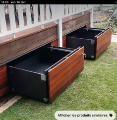 two black boxes sitting on top of grass next to a white fence and wooden slats