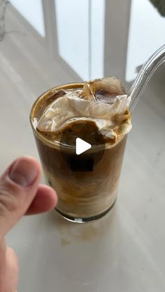 a person is pouring ice into a glass with some liquid in it on a table