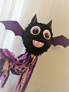 a black bat hanging from the side of a wall with purple and pink streamers