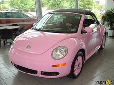 a pink car is parked in a showroom