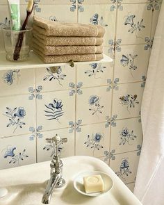 a white sink sitting under a bathroom mirror next to a shelf with towels on it